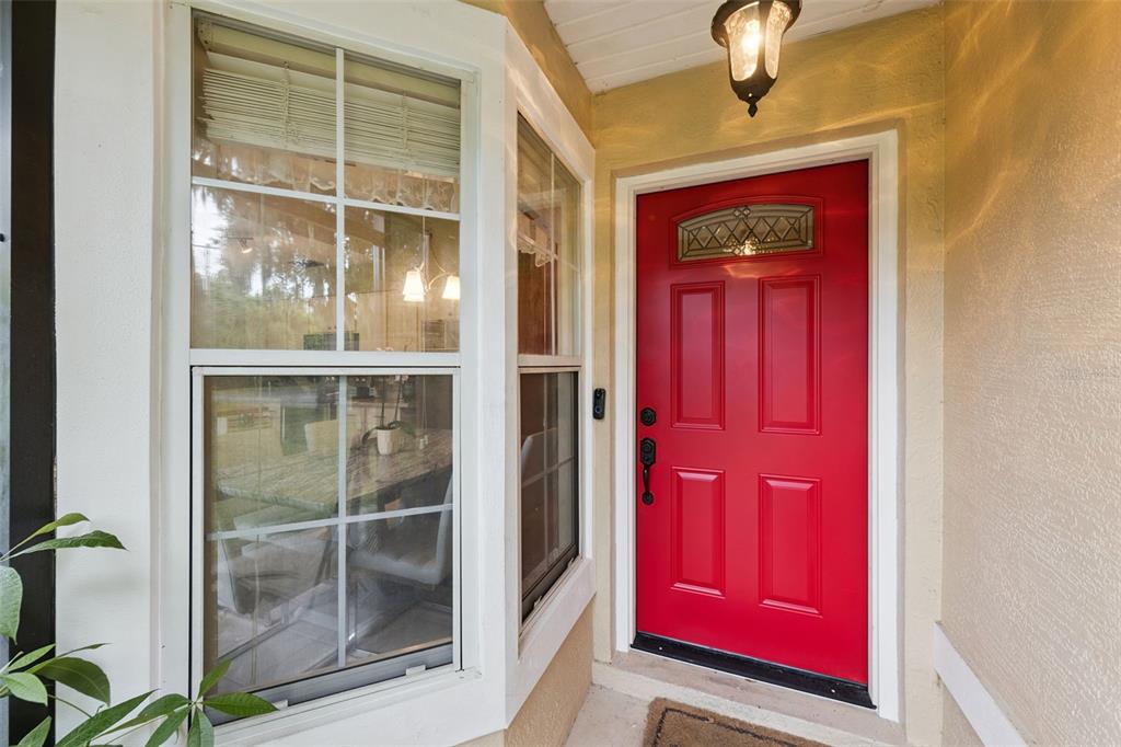 A bright red front door sits next to a bay window on a covered porch — 30724 FAIRVIEW AVENUE, TAVARES, FL