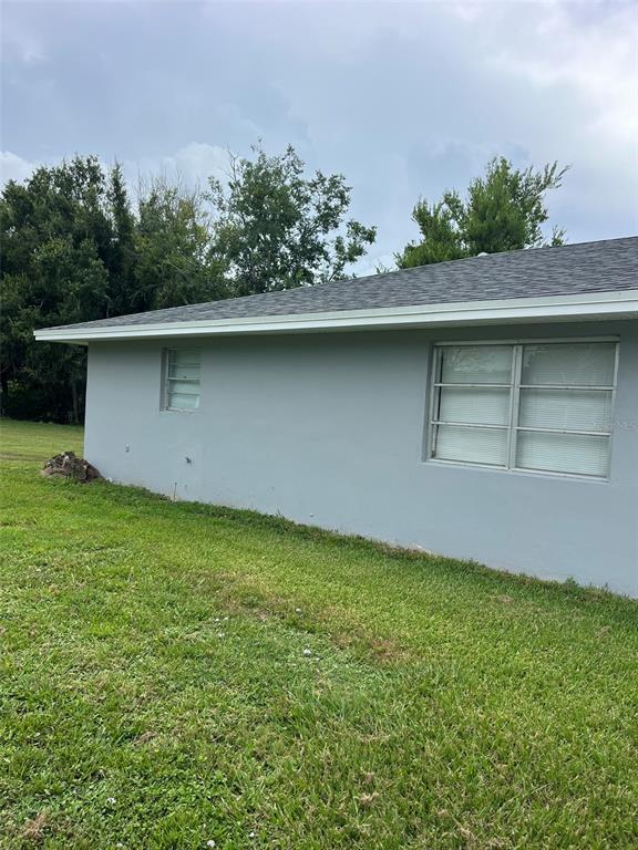 The exterior of a gray house features a shingled roof, white gutters, and two windows — 8956 SE 65TH WAY, OKEECHOBEE, FL