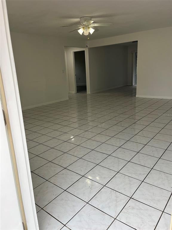 An interior view of a room with white tiled flooring and a ceiling fan — 8956 SE 65TH WAY, OKEECHOBEE, FL