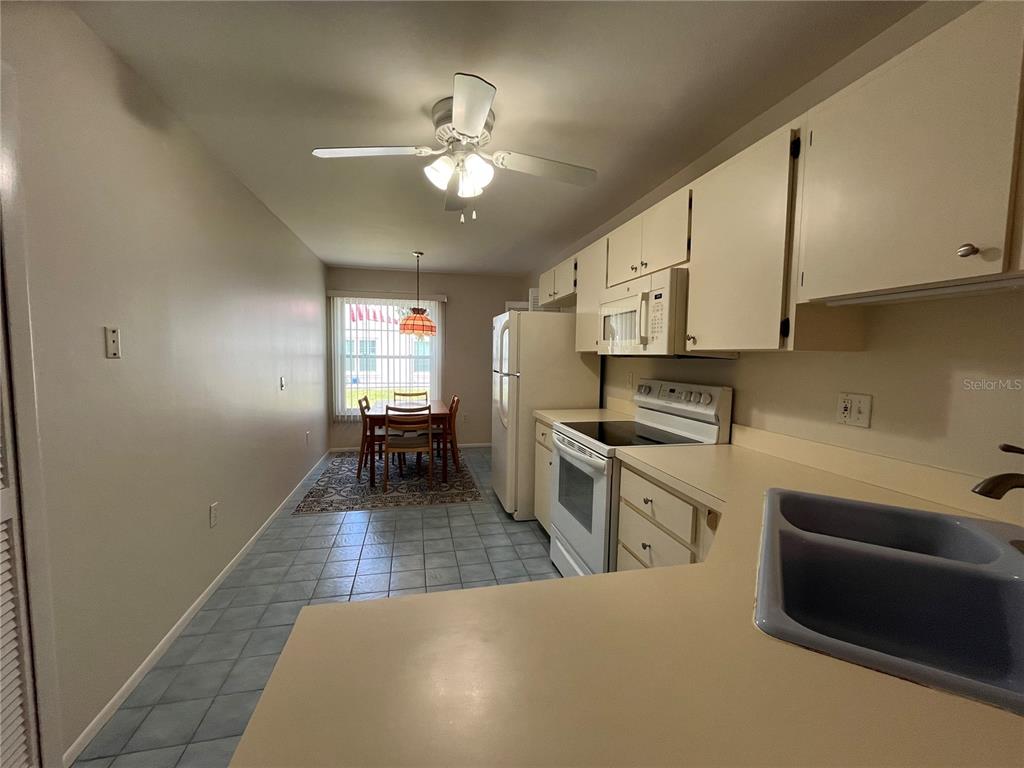 A dining room with a wooden table and chairs overlooks a kitchen and breakfast nook — 2387 BENTLEY DRIVE, PALM HARBOR, FL