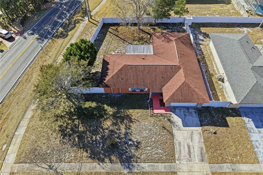 An aerial view shows a single-story house with a brown roof and a fenced yard — 7002 CRESTLAKE DRIVE, ORLANDO, FL