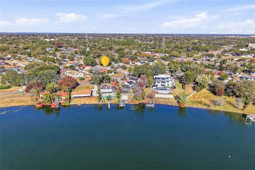 An aerial view shows several waterfront homes along a lake with docks and surrounding trees — 7002 CRESTLAKE DRIVE, ORLANDO, FL
