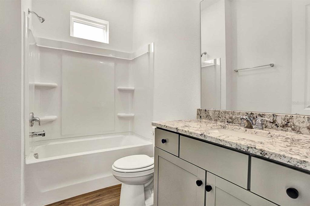 A bathroom featuring a granite vanity, gray cabinets, a toilet, and a tub-shower combination — 32 WINTERFIELD PLACE, ST AUGUSTINE, FL