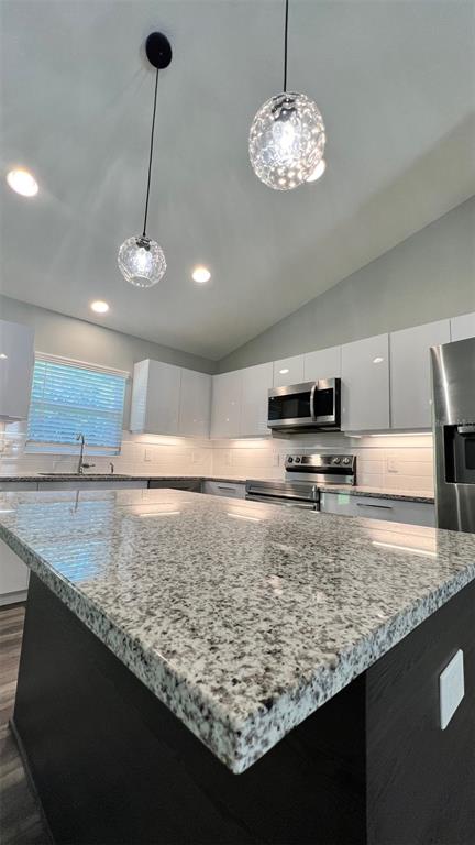 A modern kitchen features a granite-topped island, white cabinetry, stainless steel appliances, and pendant lighting — TBD BAY PLACE, OCKLAWAHA, FL