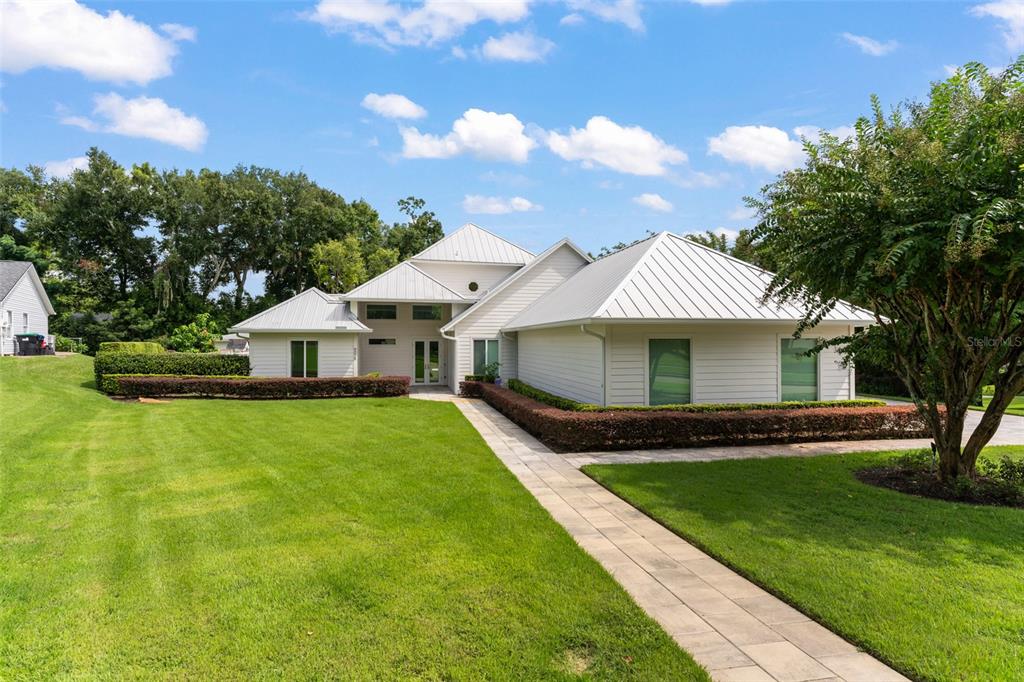A white house with a metal roof and a paved walkway through the front lawn — 9019 SPENCE COURT, GOTHA, FL