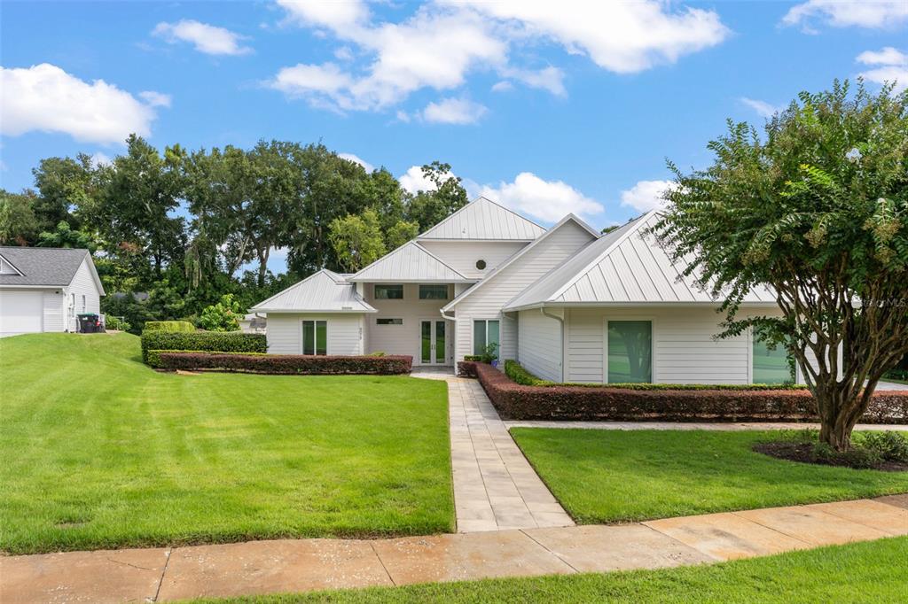 A white house with a metal roof and a paved walkway leading to the front entrance — 9019 SPENCE COURT, GOTHA, FL