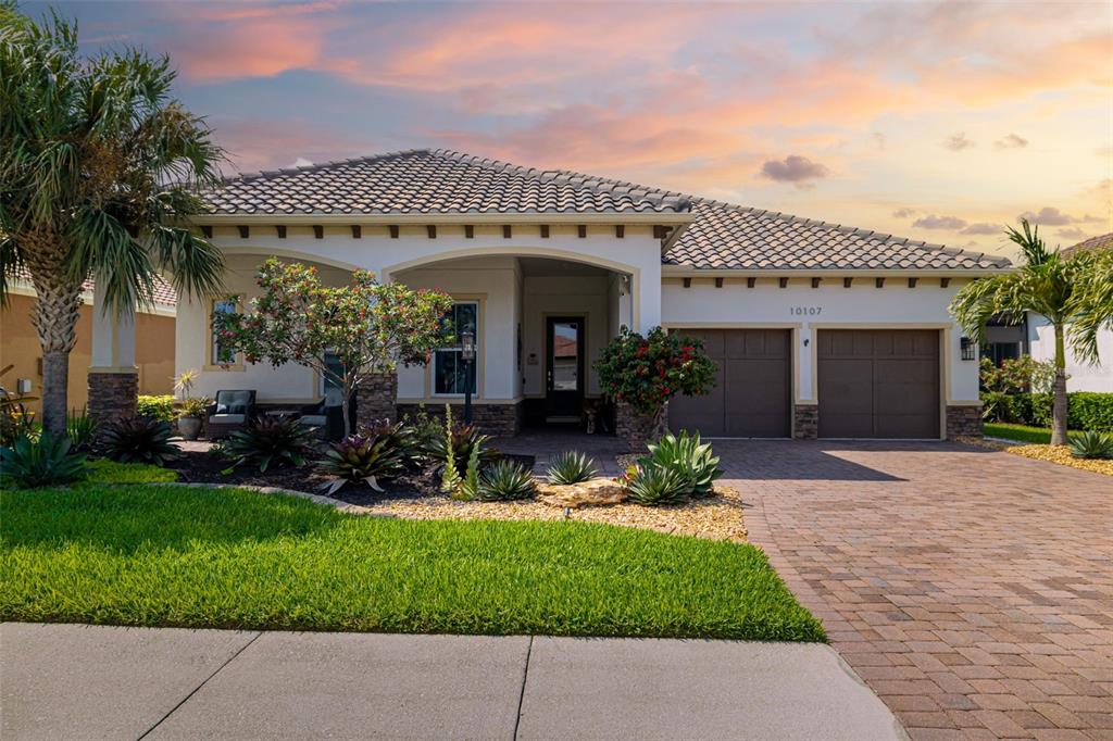 A single-story house with a tiled roof, stone accents, and a paved driveway — 10107 CARNOUSTIE PLACE, BRADENTON, FL