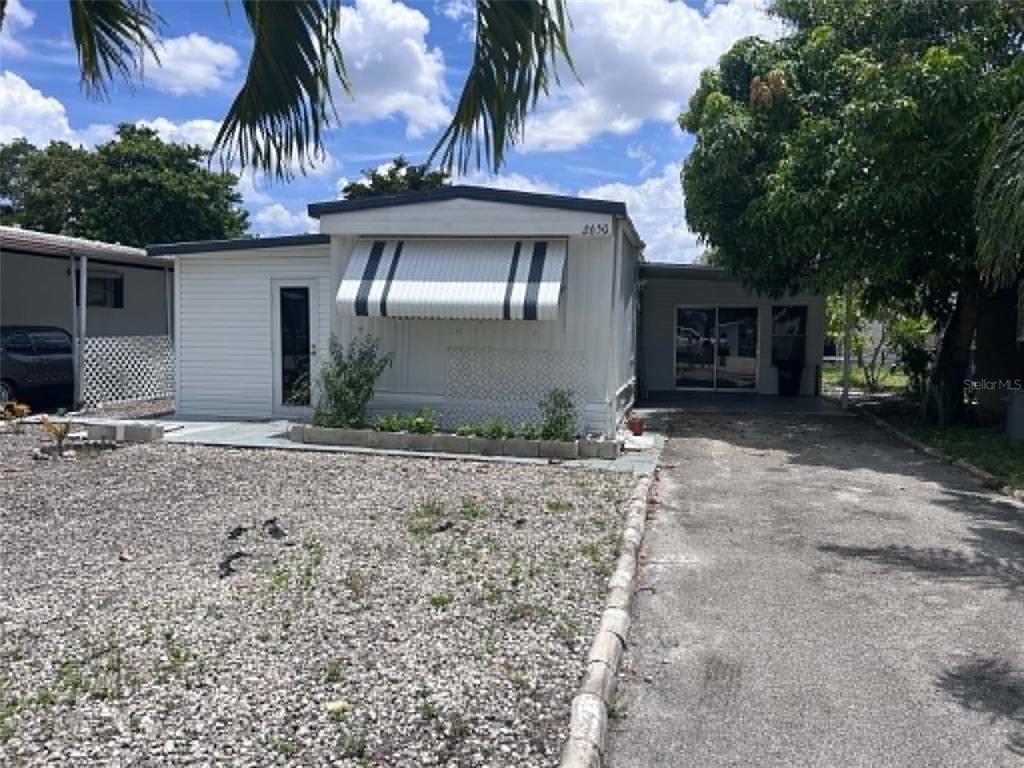 A white mobile home features a striped window awning, a gravel yard, and a paved driveway — 2650 SW 54TH PLACE, FORT LAUDERDALE, FL
