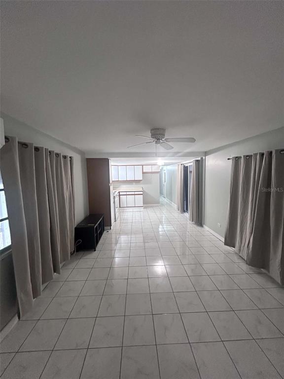 A long, open-concept room features white tile flooring, light gray walls, and a ceiling fan — 2650 SW 54TH PLACE, FORT LAUDERDALE, FL