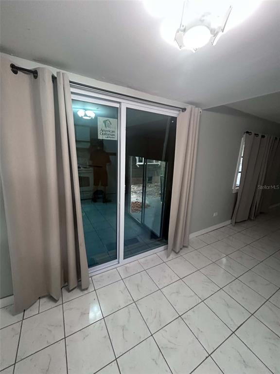 A room with light-colored tile flooring, beige curtains, and a sliding glass door — 2650 SW 54TH PLACE, FORT LAUDERDALE, FL