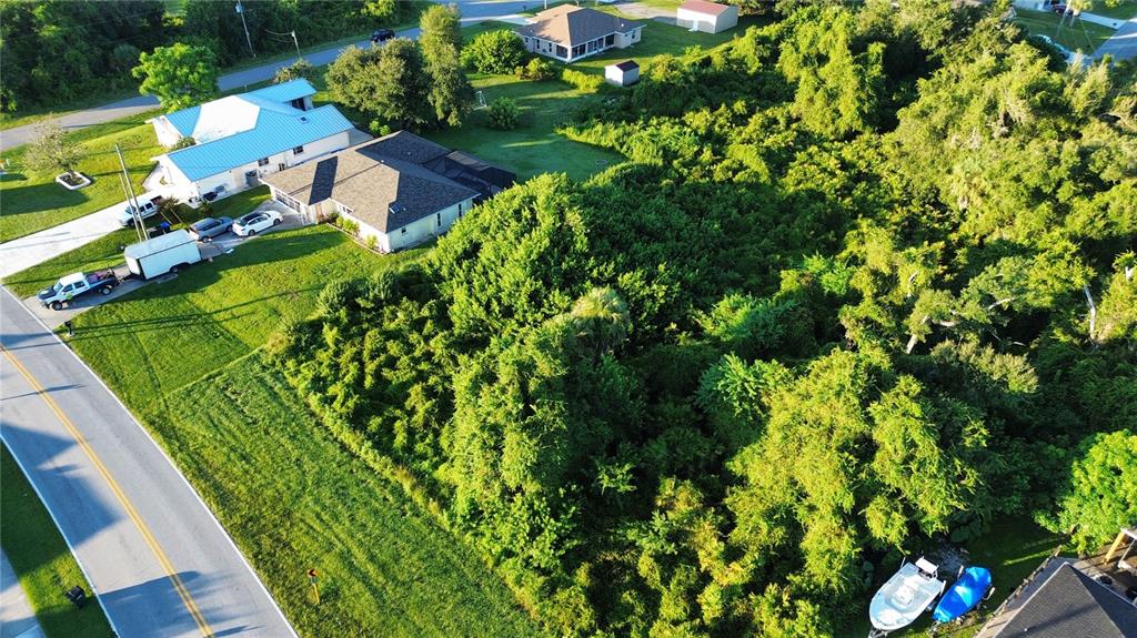 An aerial view shows a wooded lot adjacent to two houses and a paved road — S BISCAYNE DRIVE, NORTH PORT, FL