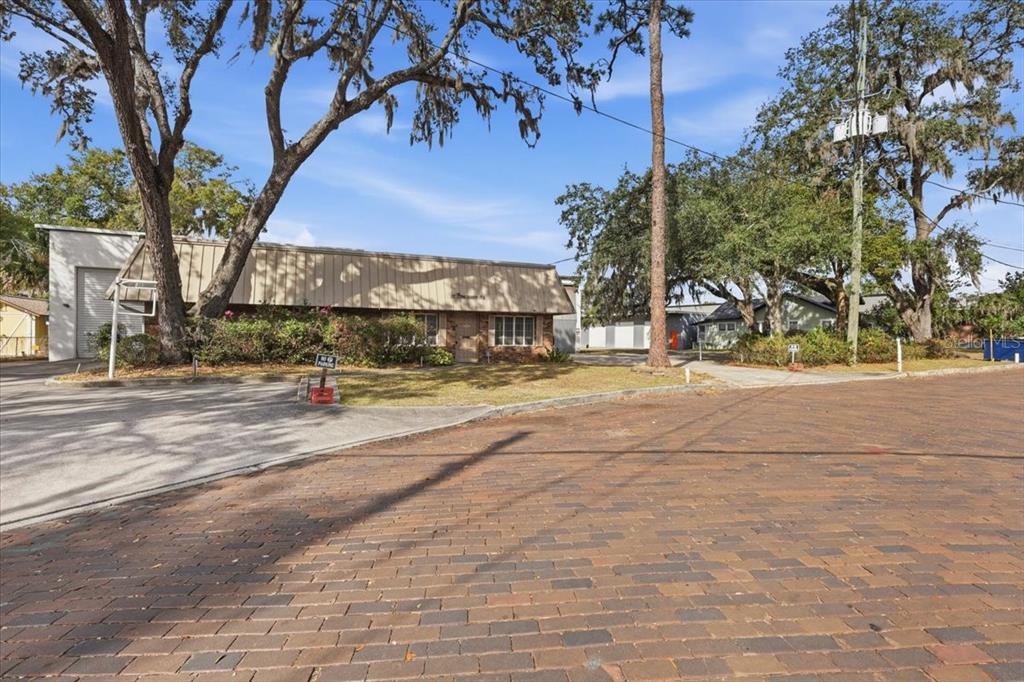 A low-slung commercial building with a metal awning sits behind a brick-paved street — 1022 WILFRED DRIVE UNIT SEALED BID!, ORLANDO, FL