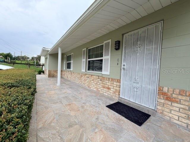 A covered porch with stone flooring leads to a front door with a decorative security gate — 606 SECOND AVENUE, LADY LAKE, FL