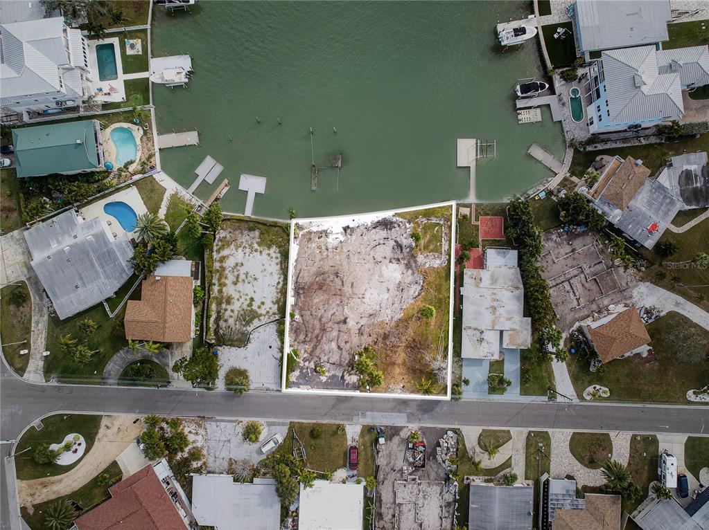 An aerial view shows a vacant waterfront lot cleared of structures between two existing houses — 409 161ST AVENUE, REDINGTON BEACH, FL
