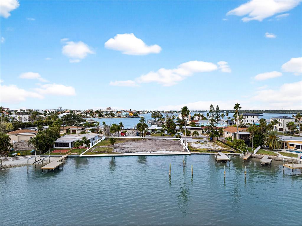 An aerial view shows a vacant waterfront lot bordered by houses and a wooden dock — 409 161ST AVENUE, REDINGTON BEACH, FL