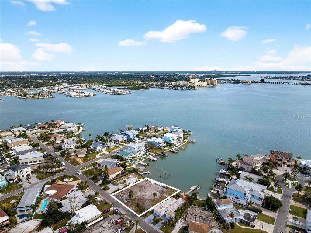 An aerial view shows a vacant waterfront lot outlined in white within a residential neighborhood — 409 161ST AVENUE, REDINGTON BEACH, FL