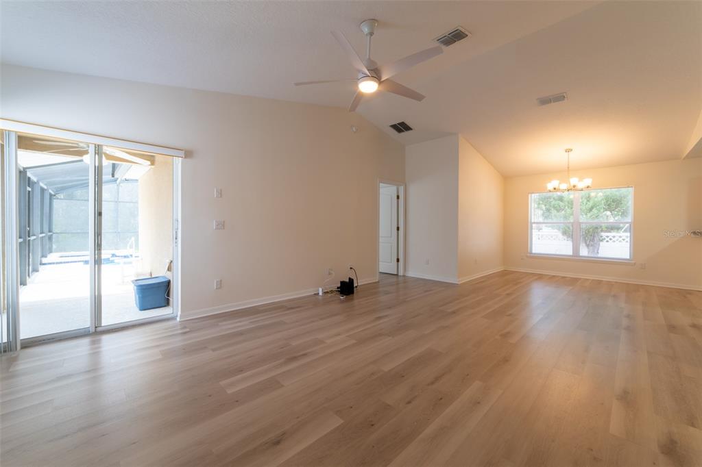 An open-concept living area with light wood-look flooring, a dining space, and a kitchen pass-through — 298 HAMMOCK COURT, DAVENPORT, FL