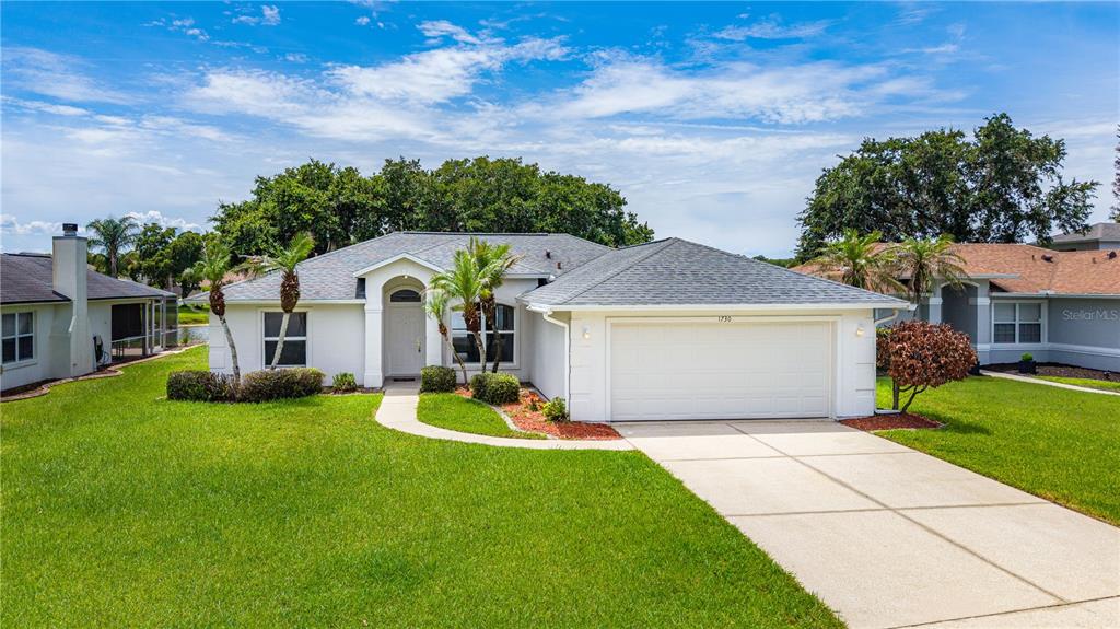 A single-story white house with a two-car garage and a front lawn under a blue sky — 1730 ARASH CIRCLE, PORT ORANGE, FL