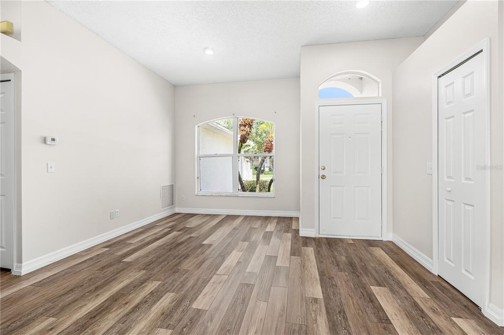An empty room with wood-look flooring, a white front door, and a large arched window — 1730 ARASH CIRCLE, PORT ORANGE, FL