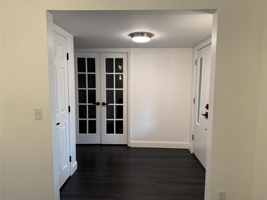 An interior entryway features dark wood flooring, white walls, French doors, and a white door — 8004 BELTREES COURT, TEMPLE TERRACE, FL