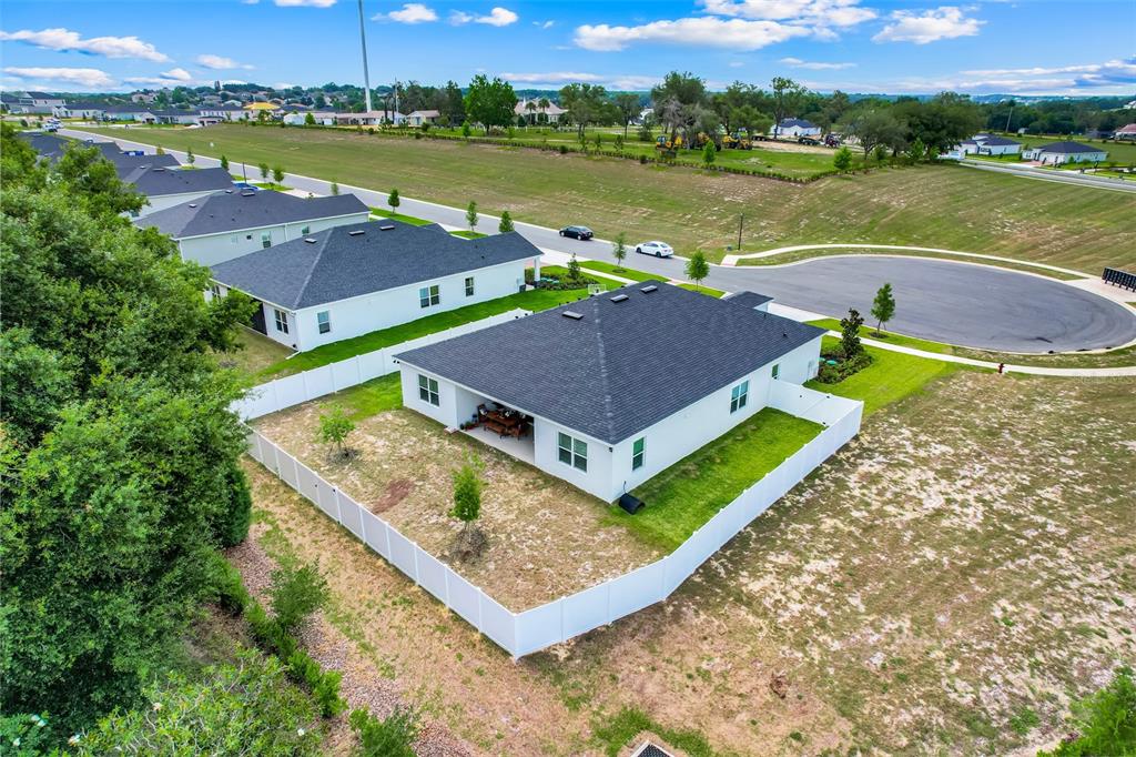 An aerial view shows a white house with a dark roof and a fenced backyard — 9844 PINE MILL COURT, CLERMONT, FL