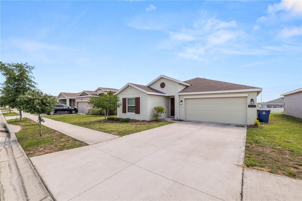 A single-story suburban house with a two-car garage, concrete driveway, and a small front lawn — 1431 LASSEN STREET, HAINES CITY, FL