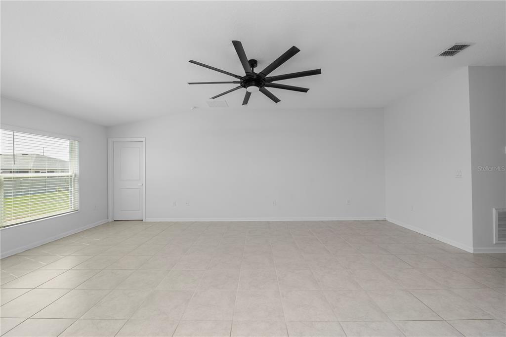 An empty room with white walls, tile flooring, and a large black ceiling fan — 1431 LASSEN STREET, HAINES CITY, FL