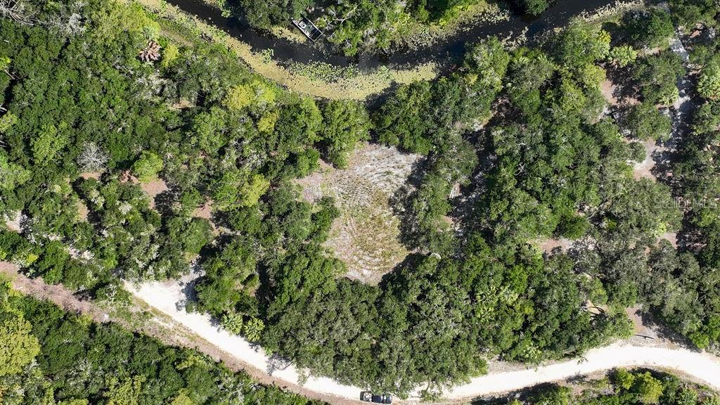 An aerial view shows a cleared, circular lot surrounded by dense trees and a winding road — 7096 E CHANNEL DRIVE, HERNANDO, FL