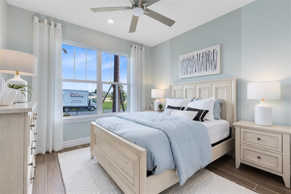 A bedroom features a light wood bed frame, blue bedding, and a window with exterior views — 5249 HANDSOME HILLS DRIVE, MOUNT DORA, FL