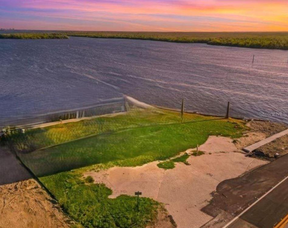 An aerial view of a vacant waterfront lot with a grassy area and paved driveway — 4767 PINE ISLAND ROAD NW, MATLACHA, FL