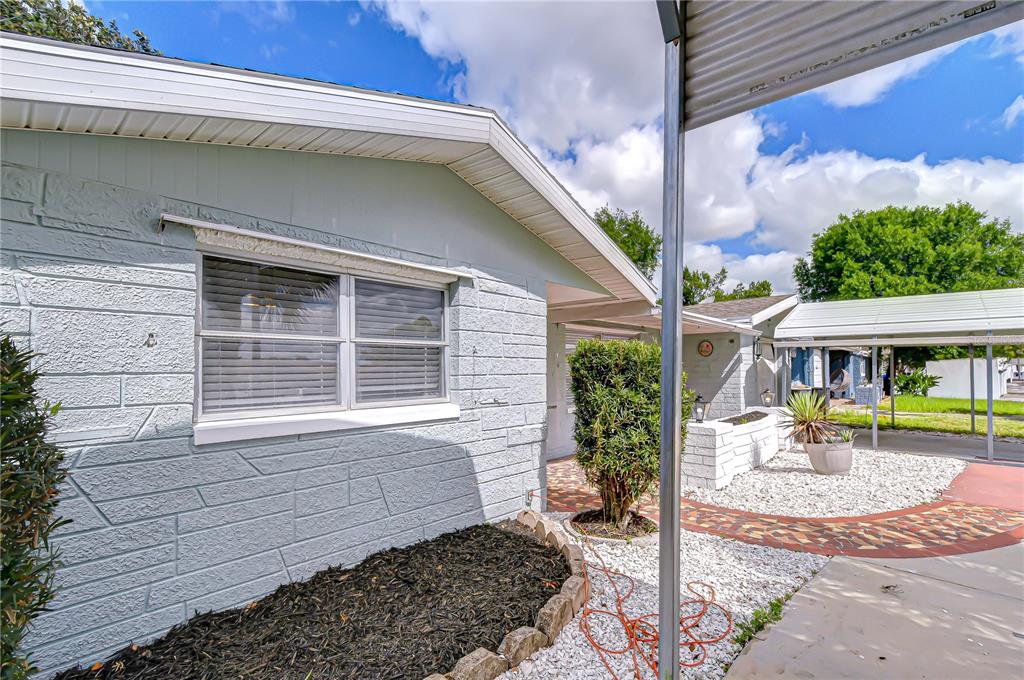 A single-story house features a concrete driveway, a metal carport, and a palm tree — 10901 OLDHAM ROAD, PORT RICHEY, FL