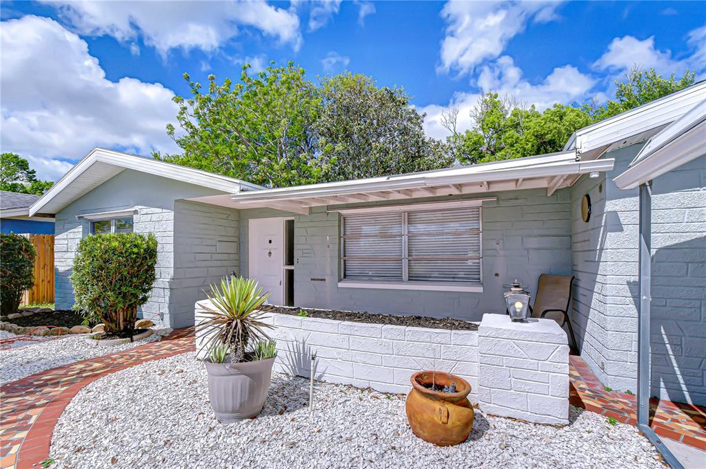 A single-story house features two metal carports, a palm tree, and a white gravel yard — 10901 OLDHAM ROAD, PORT RICHEY, FL