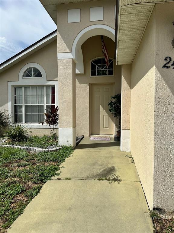 The exterior of a beige house features a concrete walkway leading to a covered entryway — 242 DURANGO LOOP STREET, DAVENPORT, FL