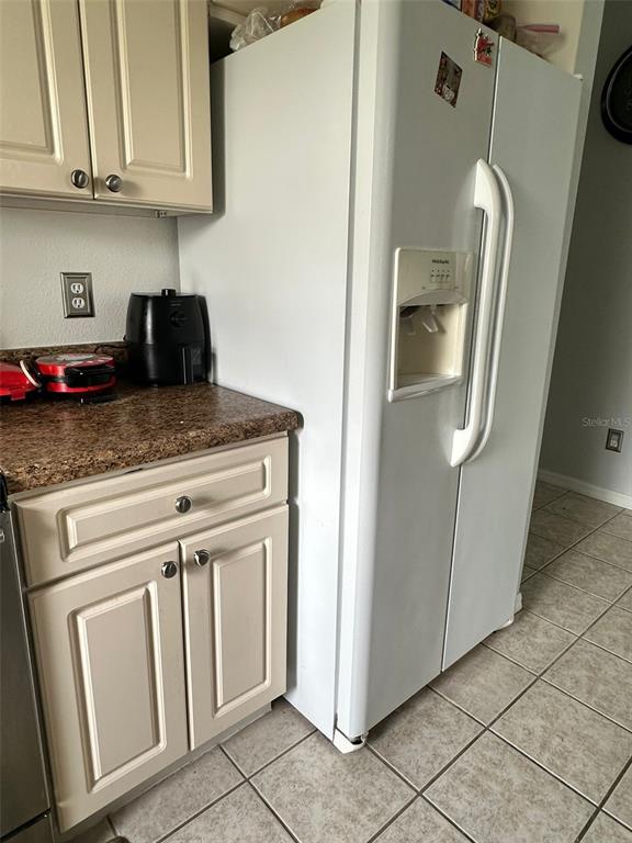 A kitchen features white cabinets, a granite countertop, and a white side-by-side refrigerator — 242 DURANGO LOOP STREET, DAVENPORT, FL