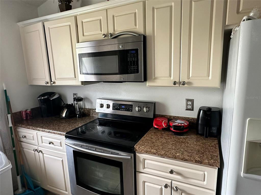 A kitchen features cream cabinets, stainless steel appliances, and speckled granite countertops — 242 DURANGO LOOP STREET, DAVENPORT, FL