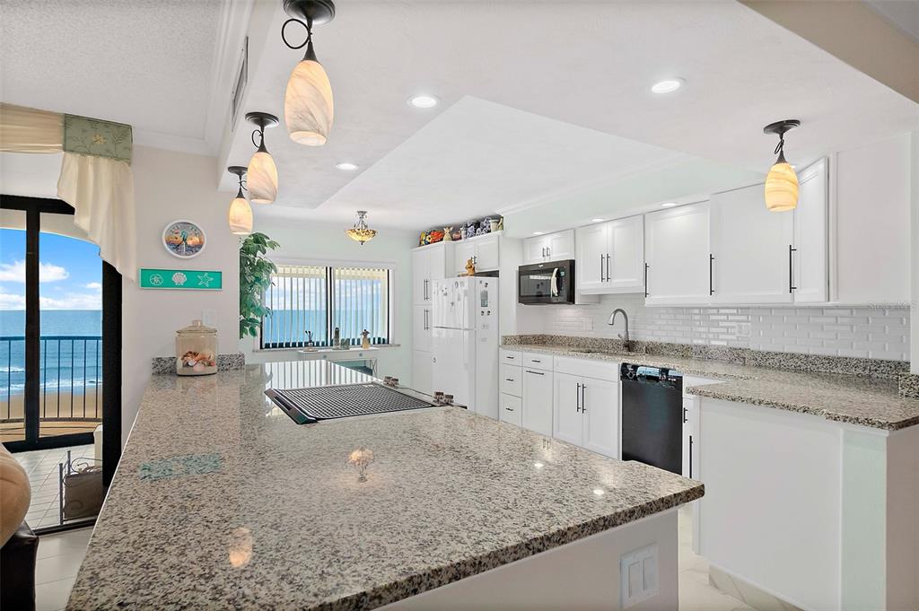 A kitchen with white cabinets, granite countertops, and a view of the ocean — 3003 S ATLANTIC AVENUE UNIT 4C5, DAYTONA BEACH SHORES, FL