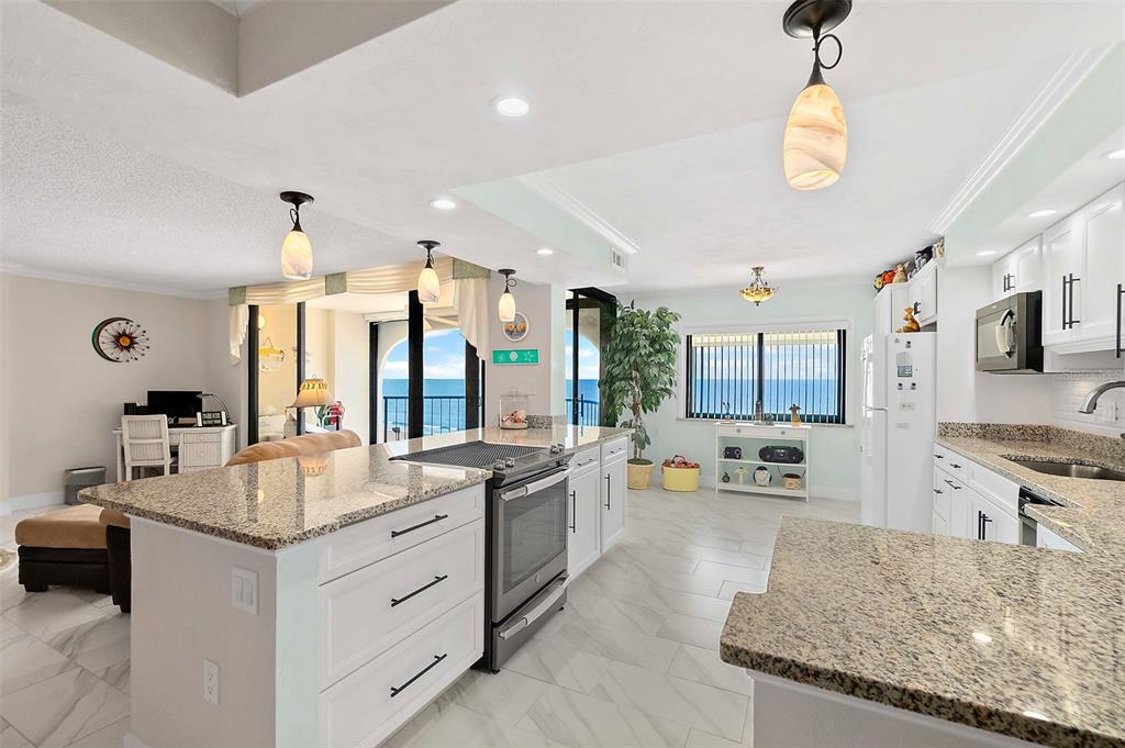 A kitchen with white cabinets, granite countertops, and an island overlooks the ocean — 3003 S ATLANTIC AVENUE UNIT 4C5, DAYTONA BEACH SHORES, FL