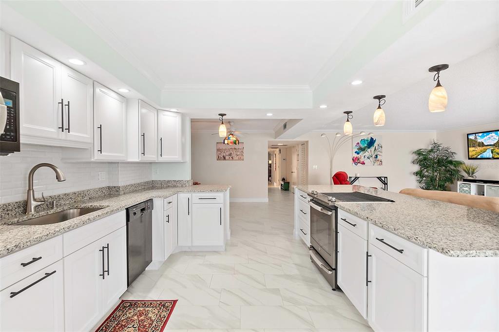 A white kitchen features granite countertops, stainless steel appliances, and light-colored tile flooring — 3003 S ATLANTIC AVENUE UNIT 4C5, DAYTONA BEACH SHORES, FL