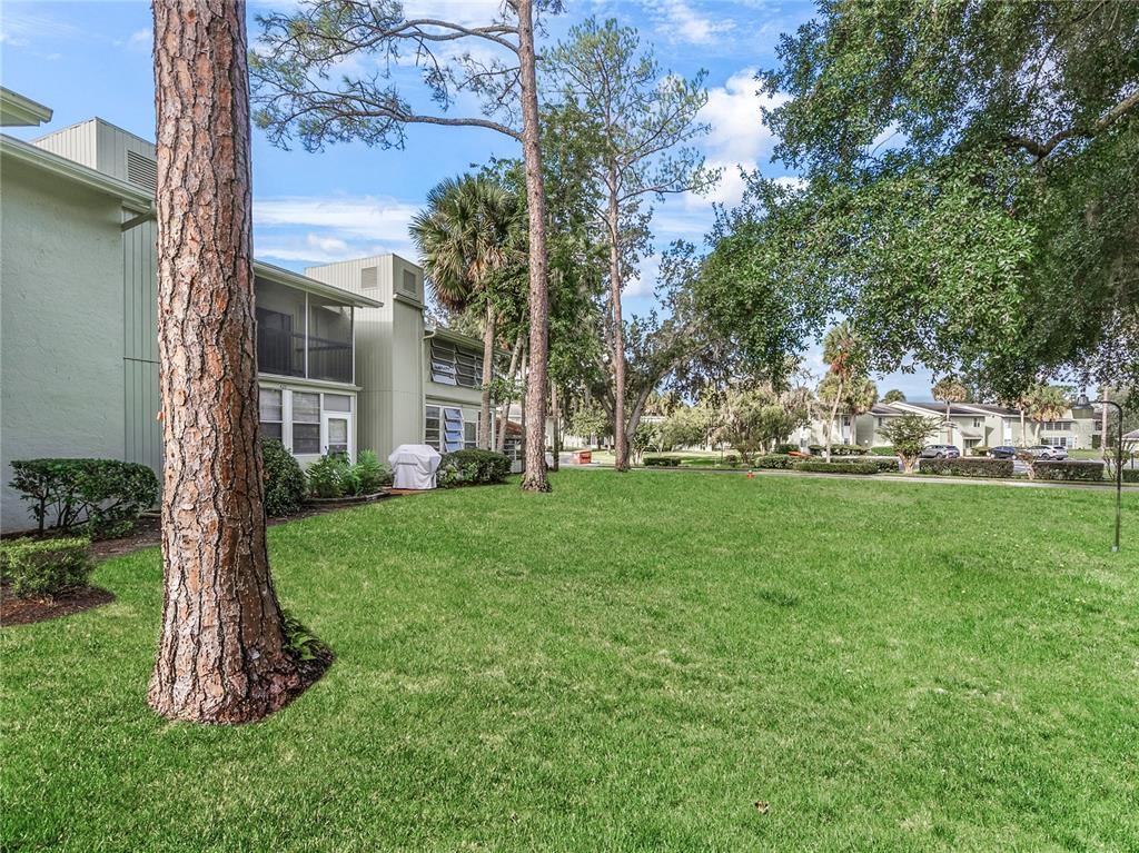 A view of a grassy lawn in front of a multi-story apartment building with trees — 622 FAIRWAYS CIRCLE UNIT A, OCALA, FL