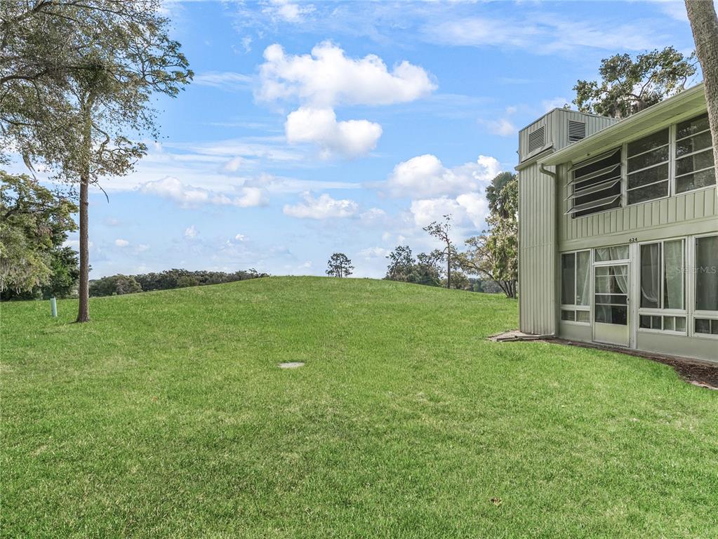 A grassy lawn leads to a two-story building with a screened porch and large windows — 622 FAIRWAYS CIRCLE UNIT A, OCALA, FL
