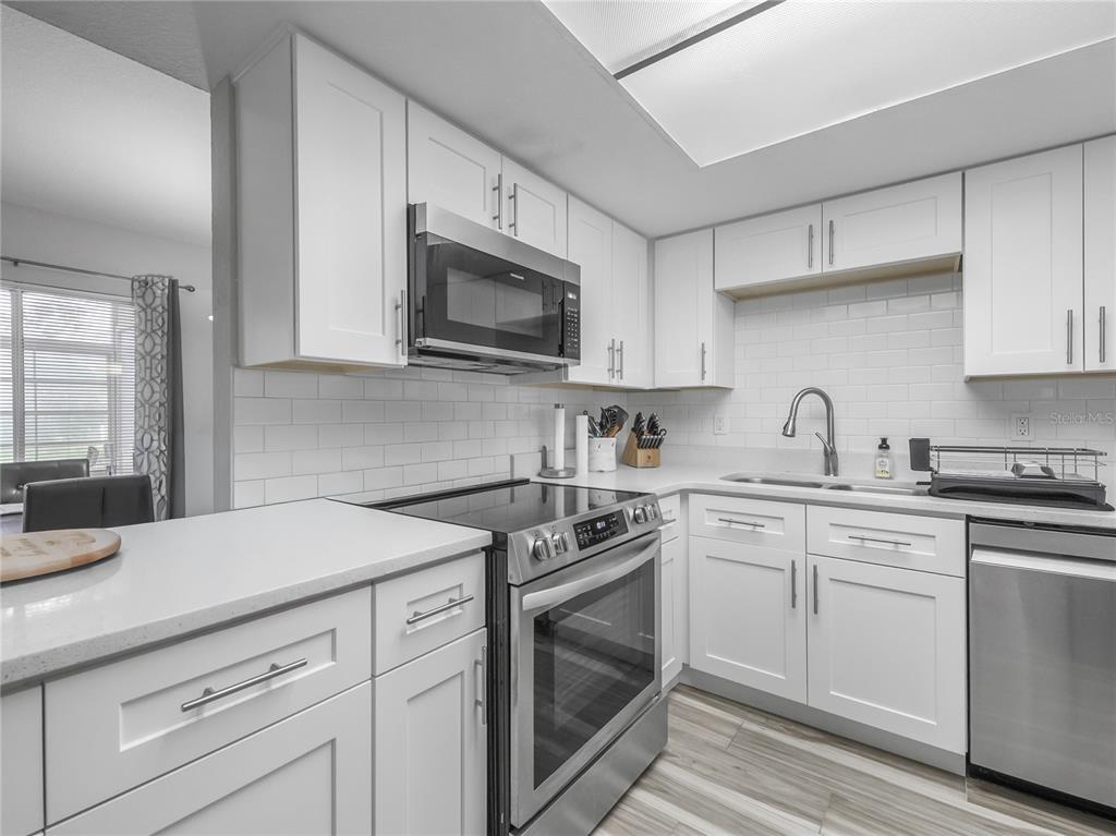 A modern kitchen features white cabinets, stainless steel appliances, and a white subway tile backsplash — 622 FAIRWAYS CIRCLE UNIT A, OCALA, FL