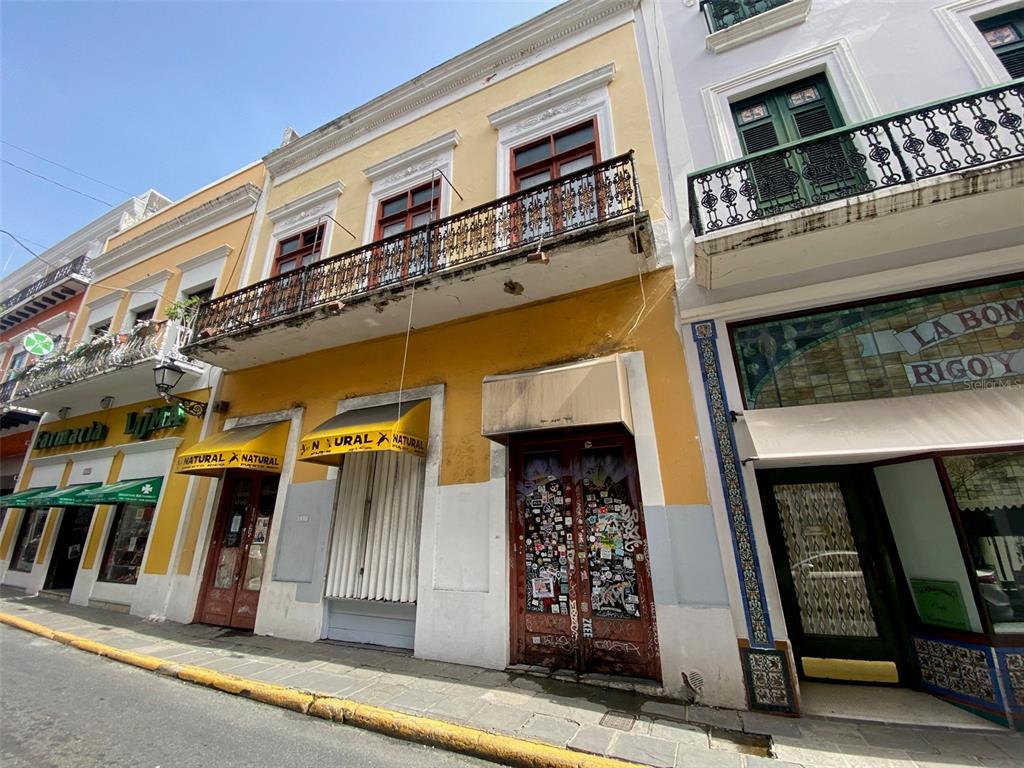 A yellow three-story building with a wrought iron balcony and storefronts on a city street — 257 SAN FRANCISCO, SAN JUAN, PR