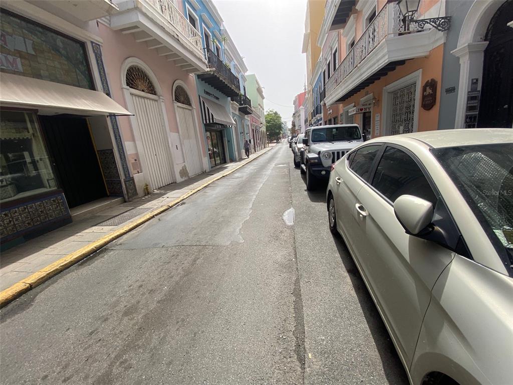 A narrow street in Old San Juan is lined with colorful historic buildings and parked cars — 257 SAN FRANCISCO, SAN JUAN, PR