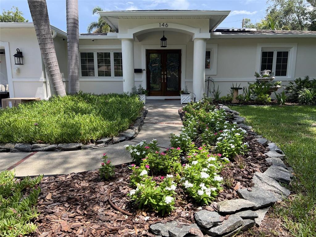 A single-story house features a covered entryway with white columns and a stone-bordered flower bed — 146 GIRALDA BOULEVARD NE, ST PETERSBURG, FL