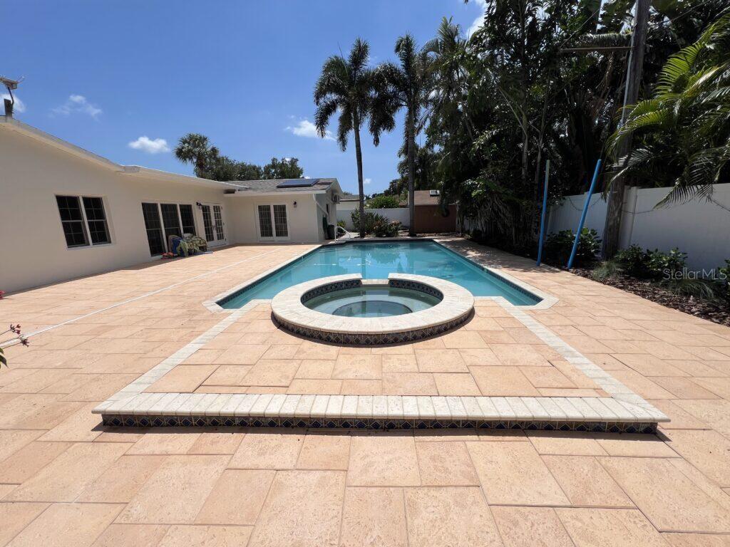 A backyard features a swimming pool with an integrated spa and a large paved patio — 146 GIRALDA BOULEVARD NE, ST PETERSBURG, FL