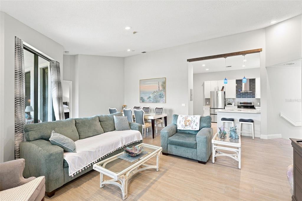 A living room with a sofa and armchair opens into a kitchen with white cabinets — 5196 EUROPA DRIVE UNIT F, BOYNTON BEACH, FL