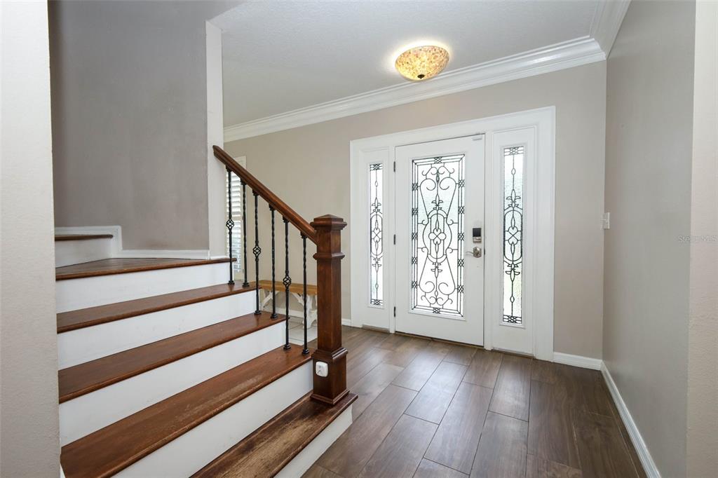 A paved walkway leads to the front entrance of a house with a gray door — 1349 VALLEY PINE CIRCLE, APOPKA, FL