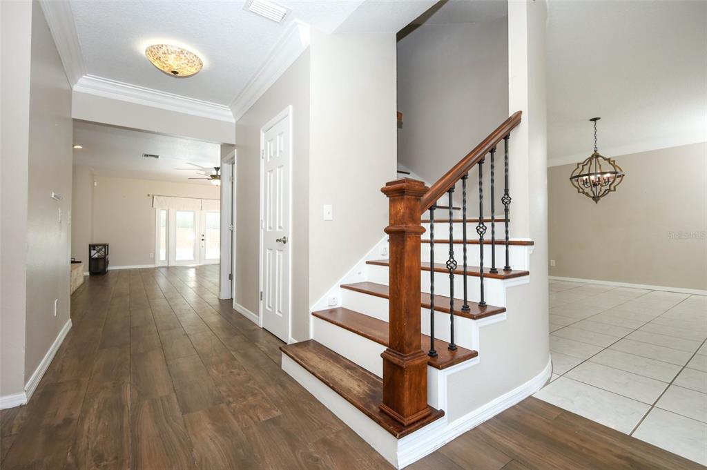 An entryway features a wooden staircase with iron railings, tile flooring, and a decorative front door — 1349 VALLEY PINE CIRCLE, APOPKA, FL