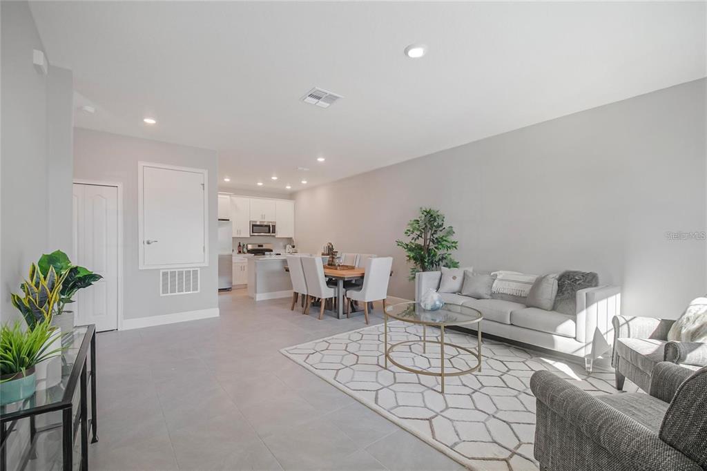 An open-concept living and dining area features light gray tile flooring and white cabinetry — 1793 CORIANDER DRIVE, POINCIANA, FL