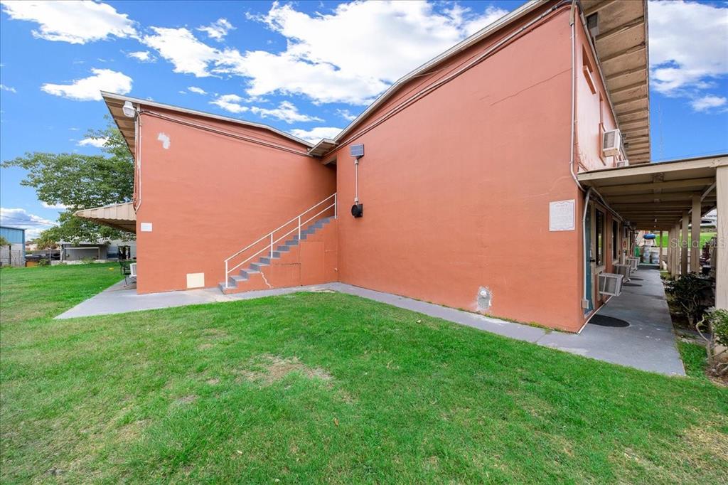 An exterior view of a two-story orange building with an outdoor staircase and covered walkway — 2210 S PINE AVENUE, OCALA, FL